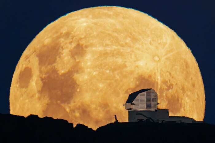 NSF–DOE Vera C. Rubin Observatory atop Cerro Pachón in Chile is outlined against the full Moon rising above the horizon. A trick of perspective has enlarged the Moon beyond the size we’d naturally see it on Earth in this Image of the Week. Often regarded as an ‘enemy’ of non-lunar astronomers because of its brightness, the beauty of Earth’s natural satellite cannot be ignored. On the right side of the Moon in this image is the large and relatively young Tycho crater, with its distinctive ray system prominently spreading across the lunar surface. On the bottom and left side are large, dark maria, basaltic plains that formed during the early life of the Moon 1.2–4 billion years ago. The largest of the maria in this image is the Sea of Tranquility, the first site on the Moon visited by humans. This image was captured during the final phase of the construction of Rubin Observatory. Starting in 2025, Rubin will conduct a decade-long survey of the Southern Sky called the Legacy Survey of Space and Time (LSST) and generate about 20 terabytes of data per night. Rubin Observatory is jointly funded by the U.S. National Science Foundation (NSF) and the U.S. Department of Energy (DOE). Rubin Observatory will begin science operations in late 2025. Rubin Observatory is a Program of NSF NOIRLab, which, along with SLAC National Accelerator Laboratory, will jointly operate Rubin. This photo was taken by Hernán Stockebrand, a NOIRLab Audiovisual Ambassador.